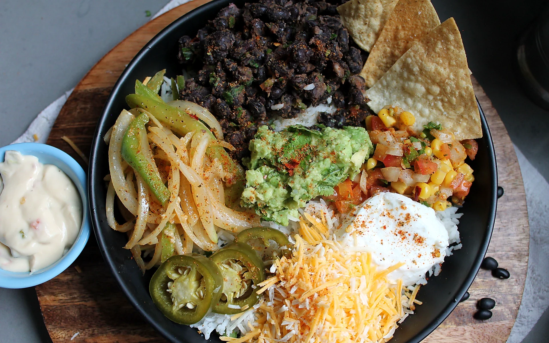 Colorful burrito bowl with black beans, rice, guacamole, salsa and cheese