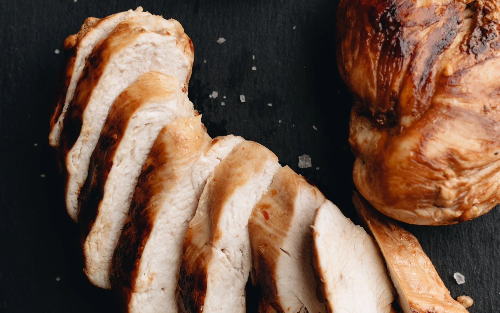 Sliced roasted chicken breast showing a browned exterior and moist interior
